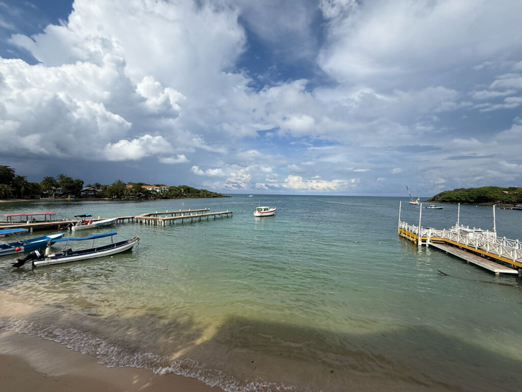 Expansive view of Half Moon Bay in Roatan Honduras, clear, clean water and blue cloudy skies
