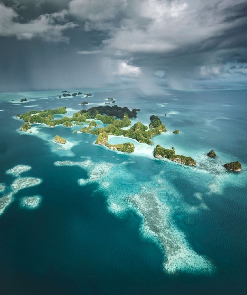 Aerial view of the spotted islands of Palau amidst a distant storm pouring from the clouds