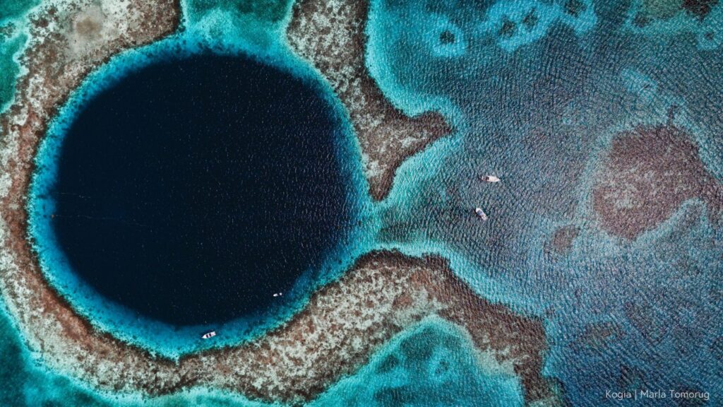 Giant blue hole surrounded by turquoise reefs